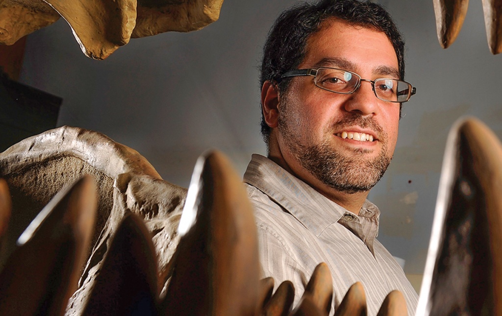 Matthew Carrano ’91 grins alongside some dinosaur teeth