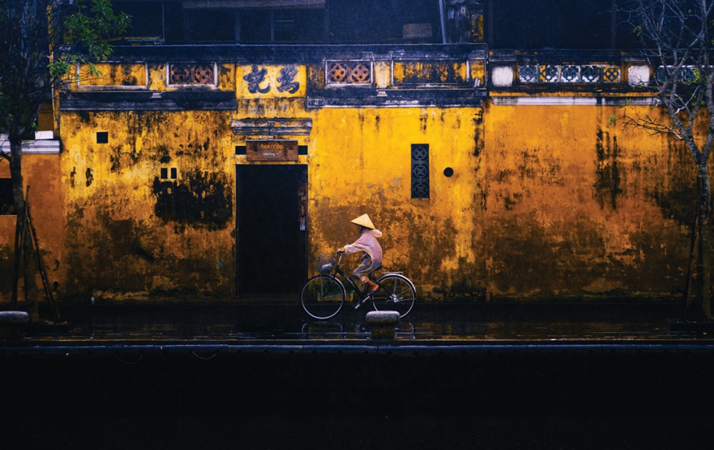 Photograph of a bicyclist in front of a colorful building