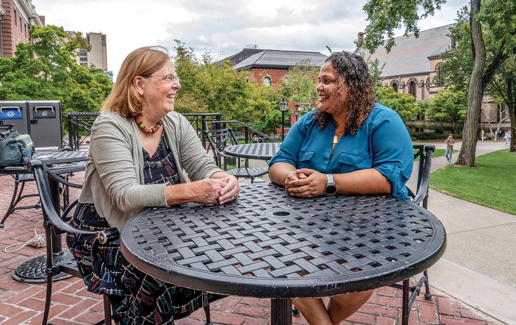 Image of Karen McAninch ’74 and Guadalete Ramos sitting at a table on the main green