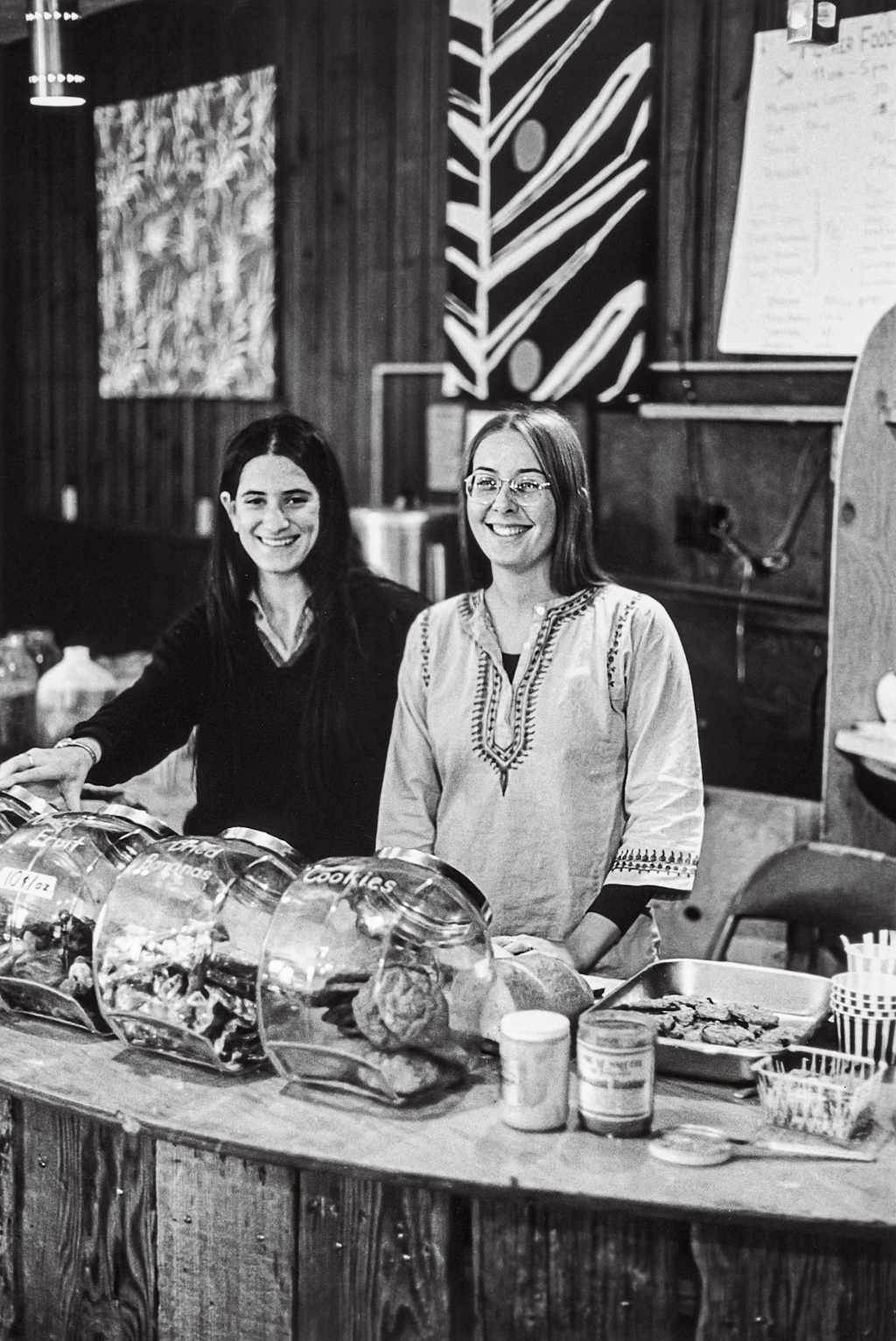 Image of Leslie Seeman and Barb Goldman standing behind the counter in the 1970's Brown University coffeeshop "Big Mother"