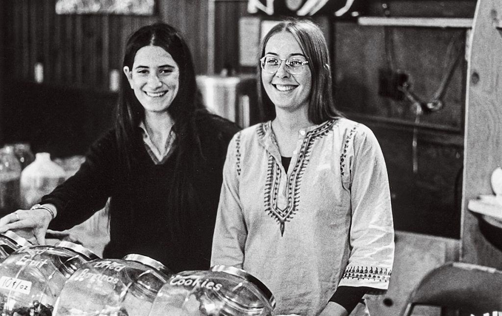 Image of Leslie Seeman and Barb Goldman standing behind the counter in the 1970's Brown University coffeeshop "Big Mother"