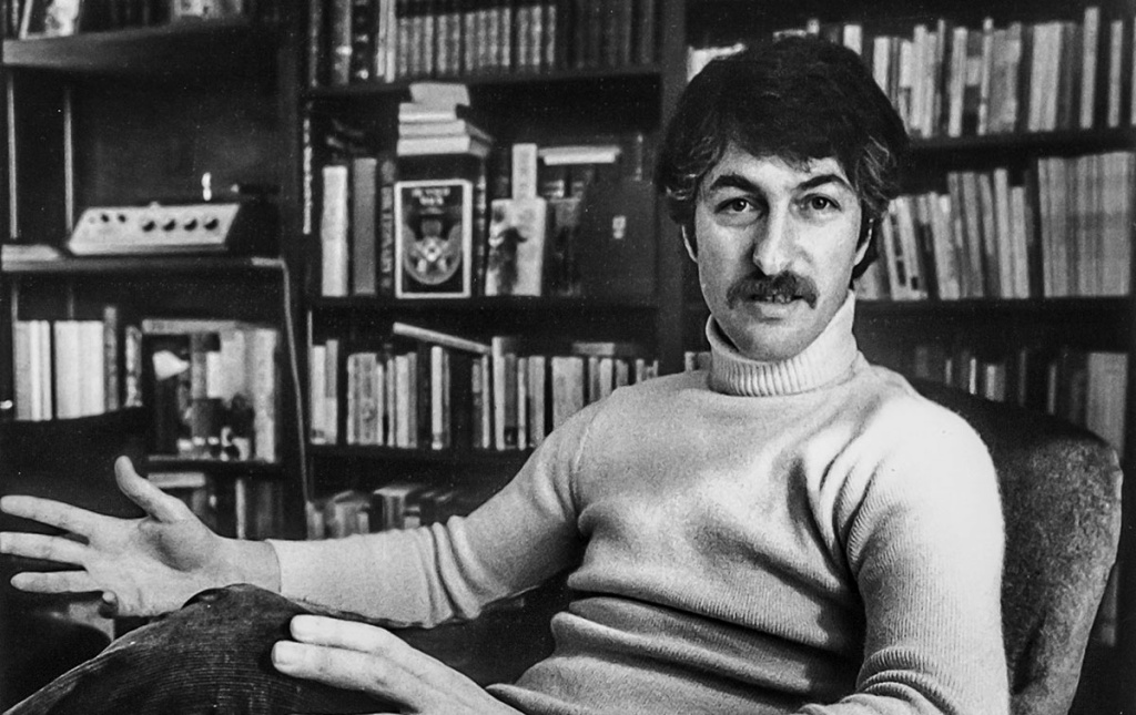 Black and white image of Arnold Weinstein sitting in a chair with books in the background in March 1974.