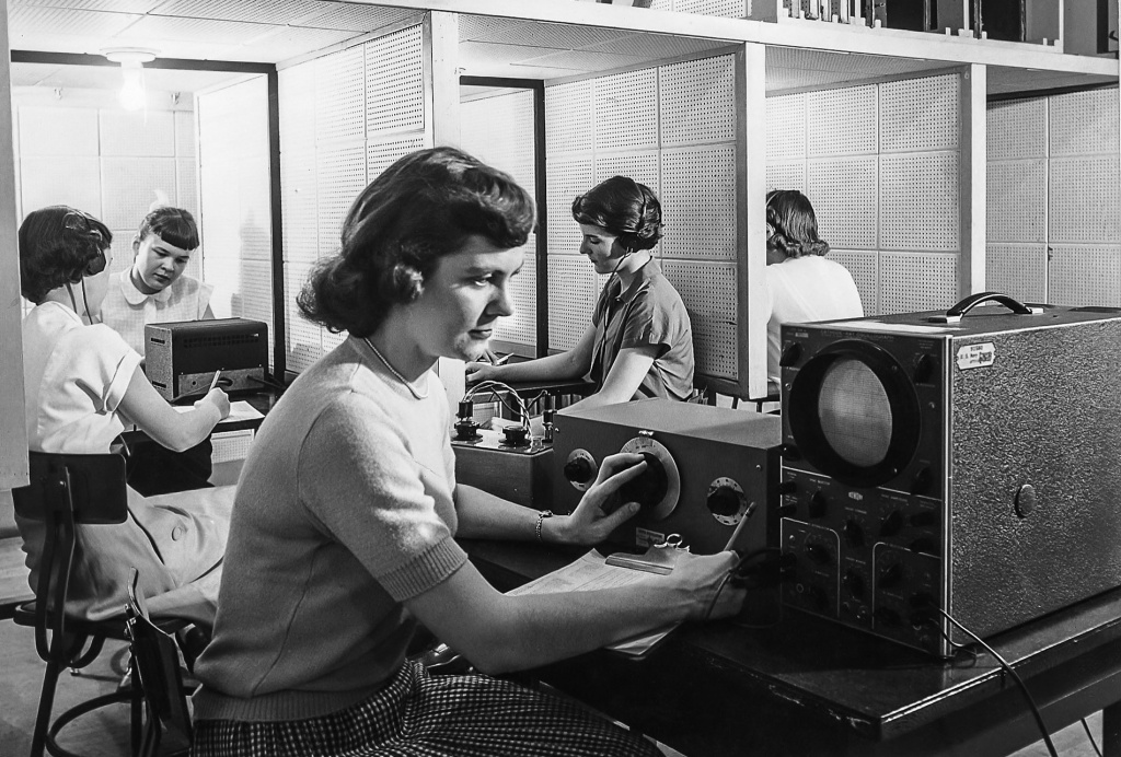 Archival image of students using machines in a Psych lab.