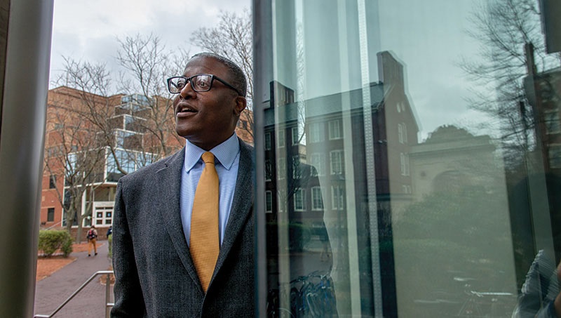 Photograph of Jason Sello standing by a glass building.