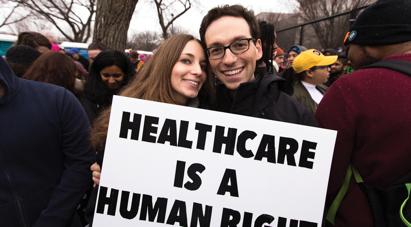 Photo of Kira Ganga Kieffer ’08 and Aaron Eisman ’08, at a rally with a sign that says "Healthcare is a Human Right."