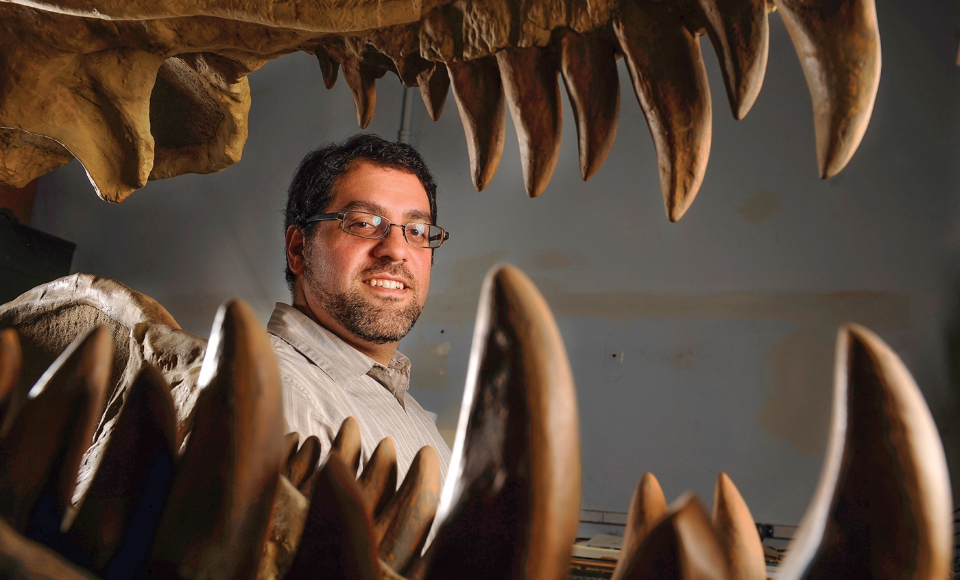 Matthew Carrano ’91 grins alongside some dinosaur teeth