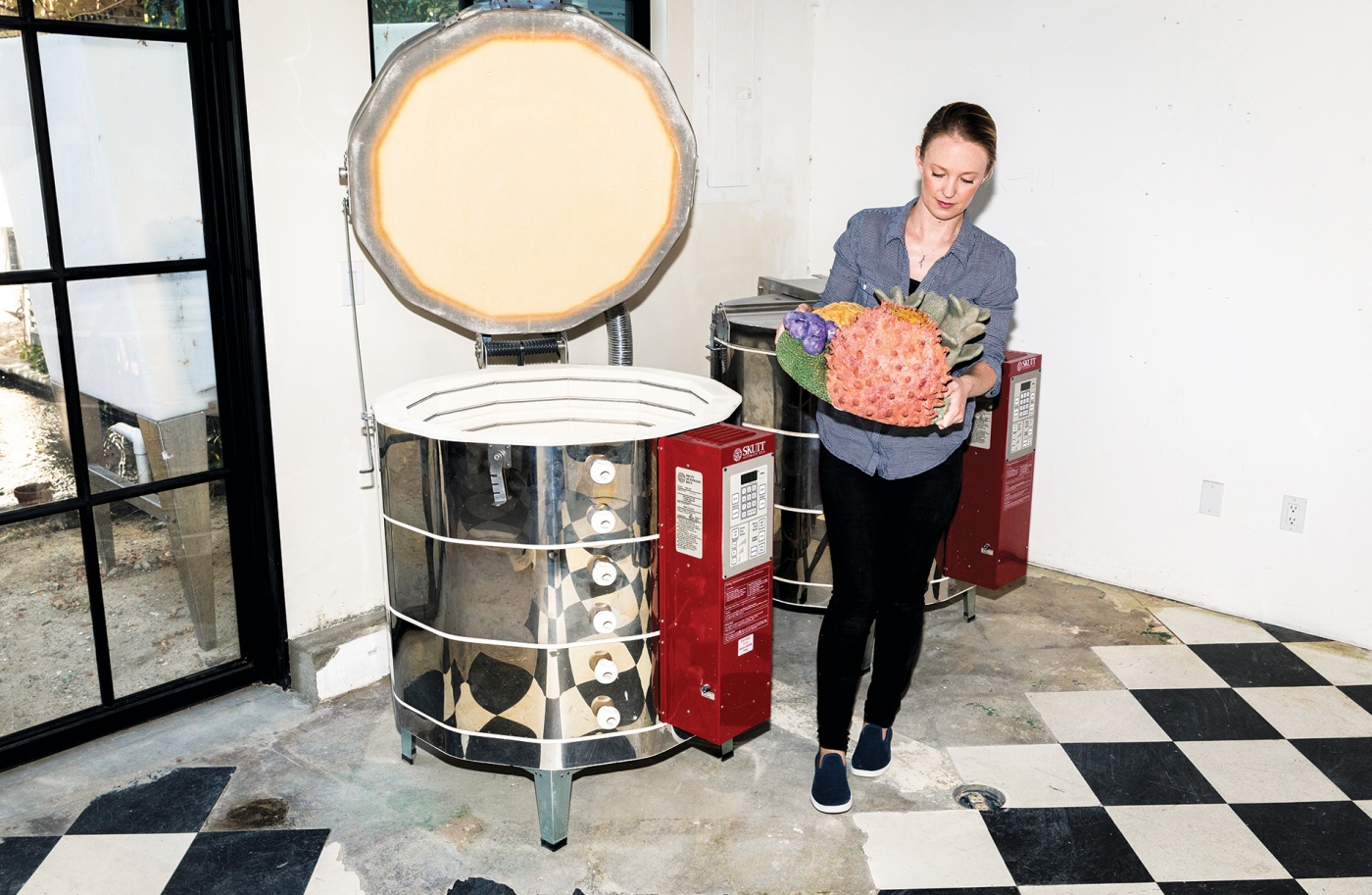 Courtney Mattisson removes a ceramic piece from the kiln in her studio