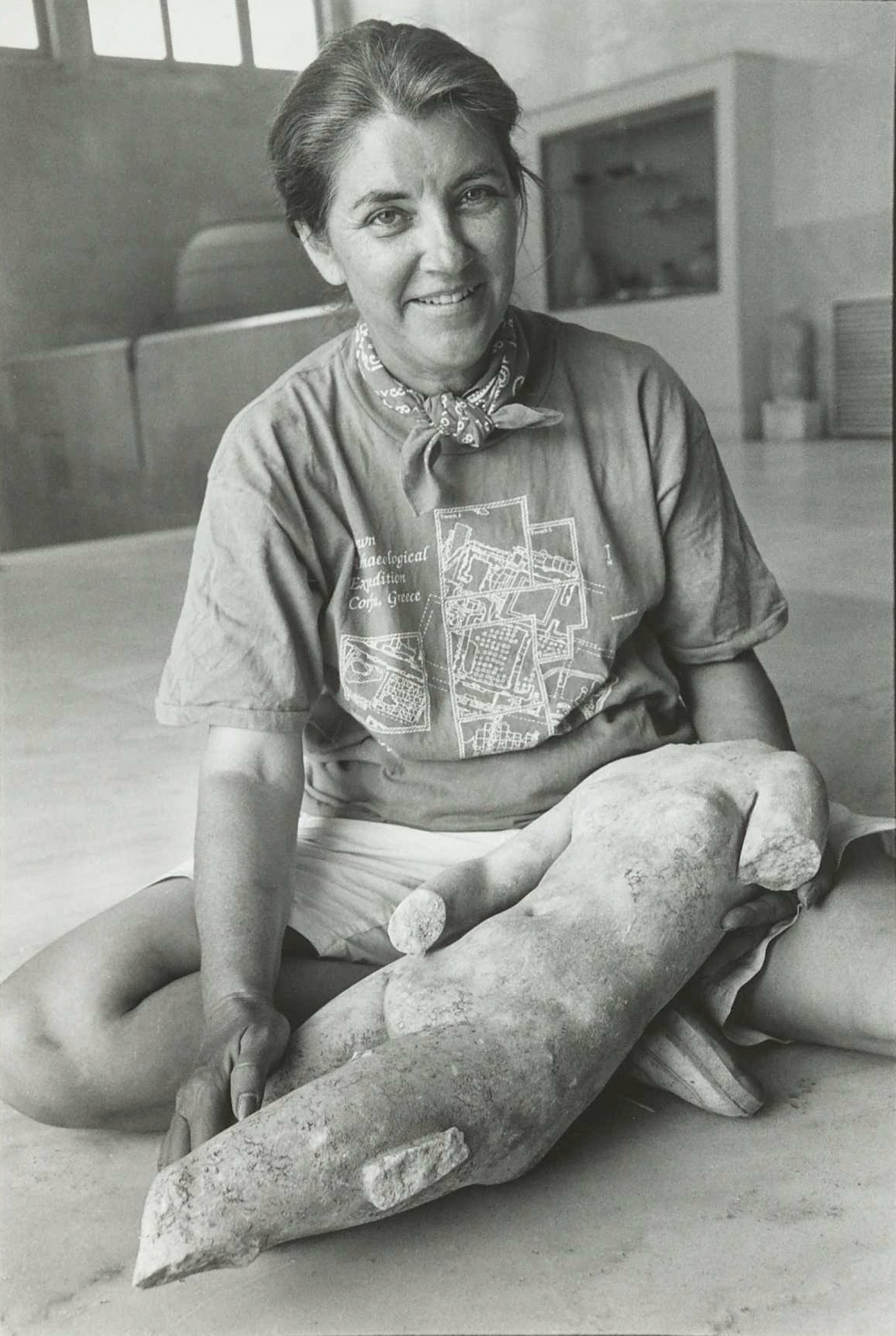 Black and white image of Martha Joukowsky at Brown University holding an unknown object