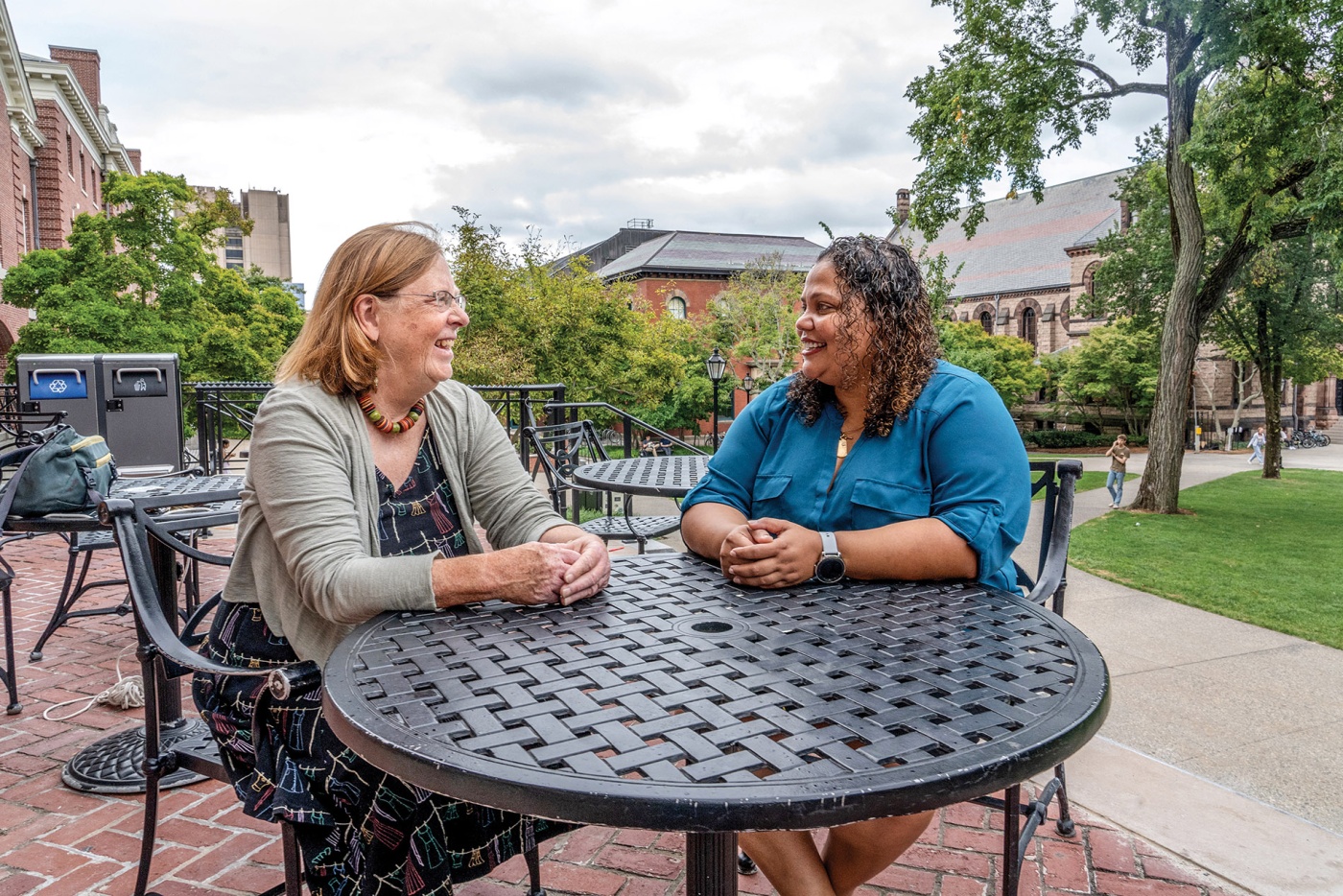 Image of Karen McAninch ’74 and Guadalete Ramos sitting at a table on the main green