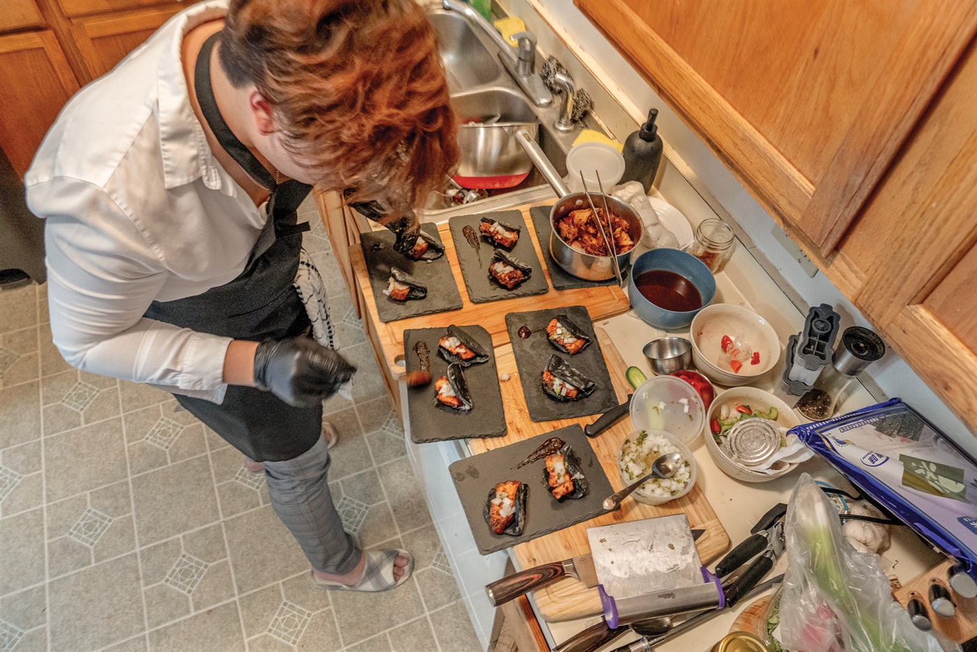 Image of Ryan Lum fixing food on the counter for his supper club.