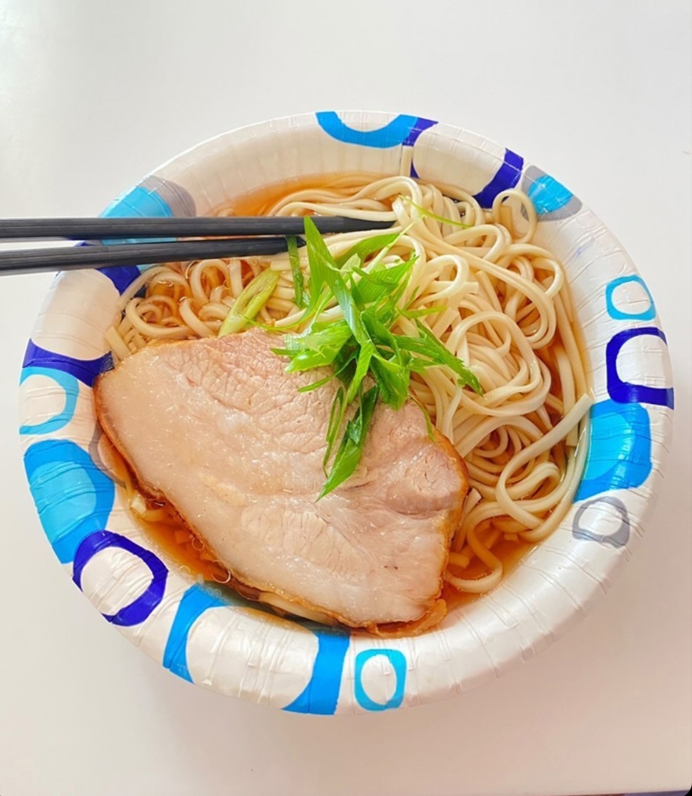 Paper bowl of dashi with udon and chashu