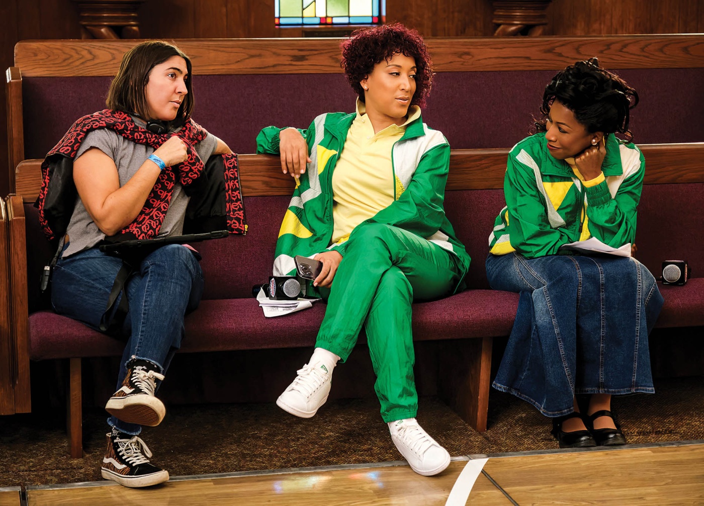 Image of Bridget Stokes on set; sitting with Robin Thede and Gabrielle Dennis on a bench.