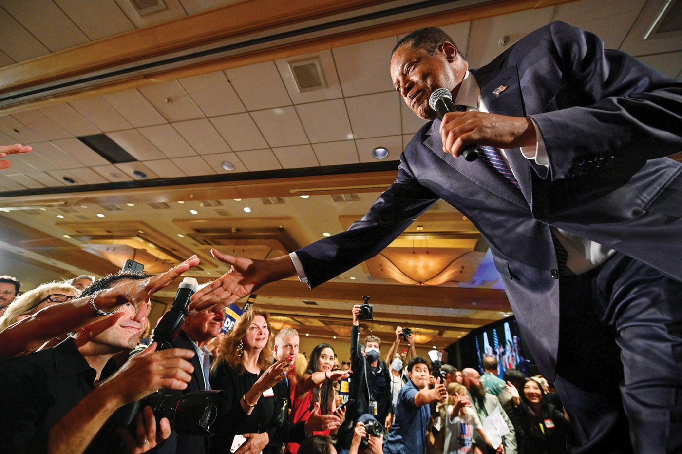 Larry Elder shakes hands from the stage