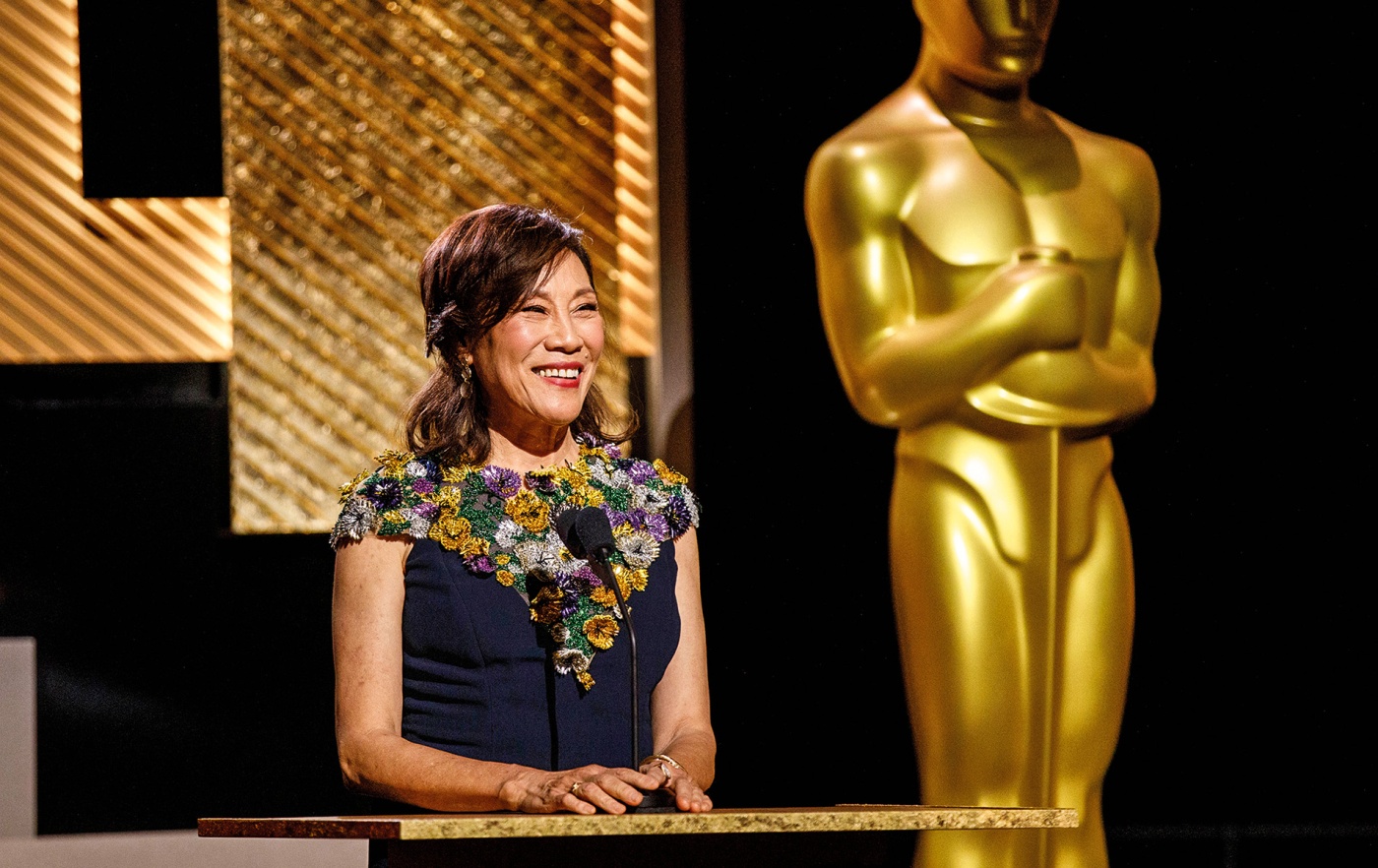Image of Janet Yang on stage at the Academy Awards with the life-sized Oscar behind her