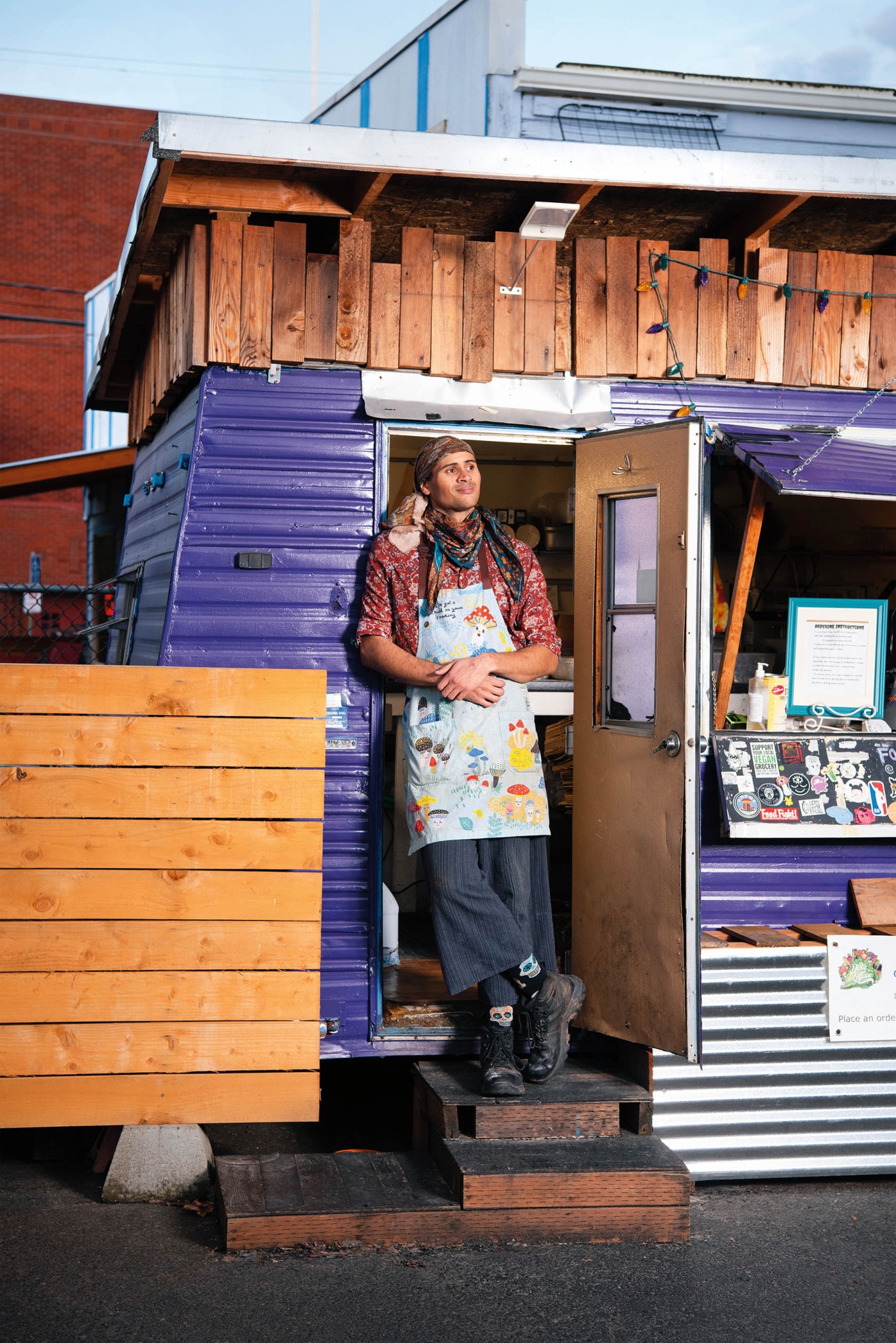 Image of Alkebulan Moroski standing in the door of a food trailer wearing an apron.