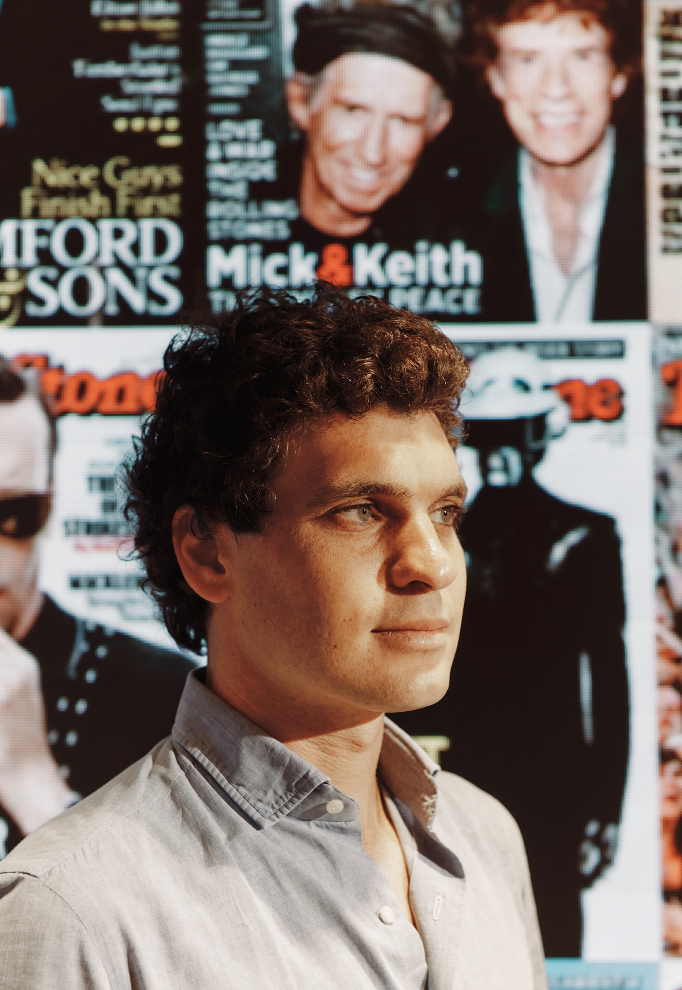 portrait of Gus Wenner in front of a wall of Rolling Stone covers