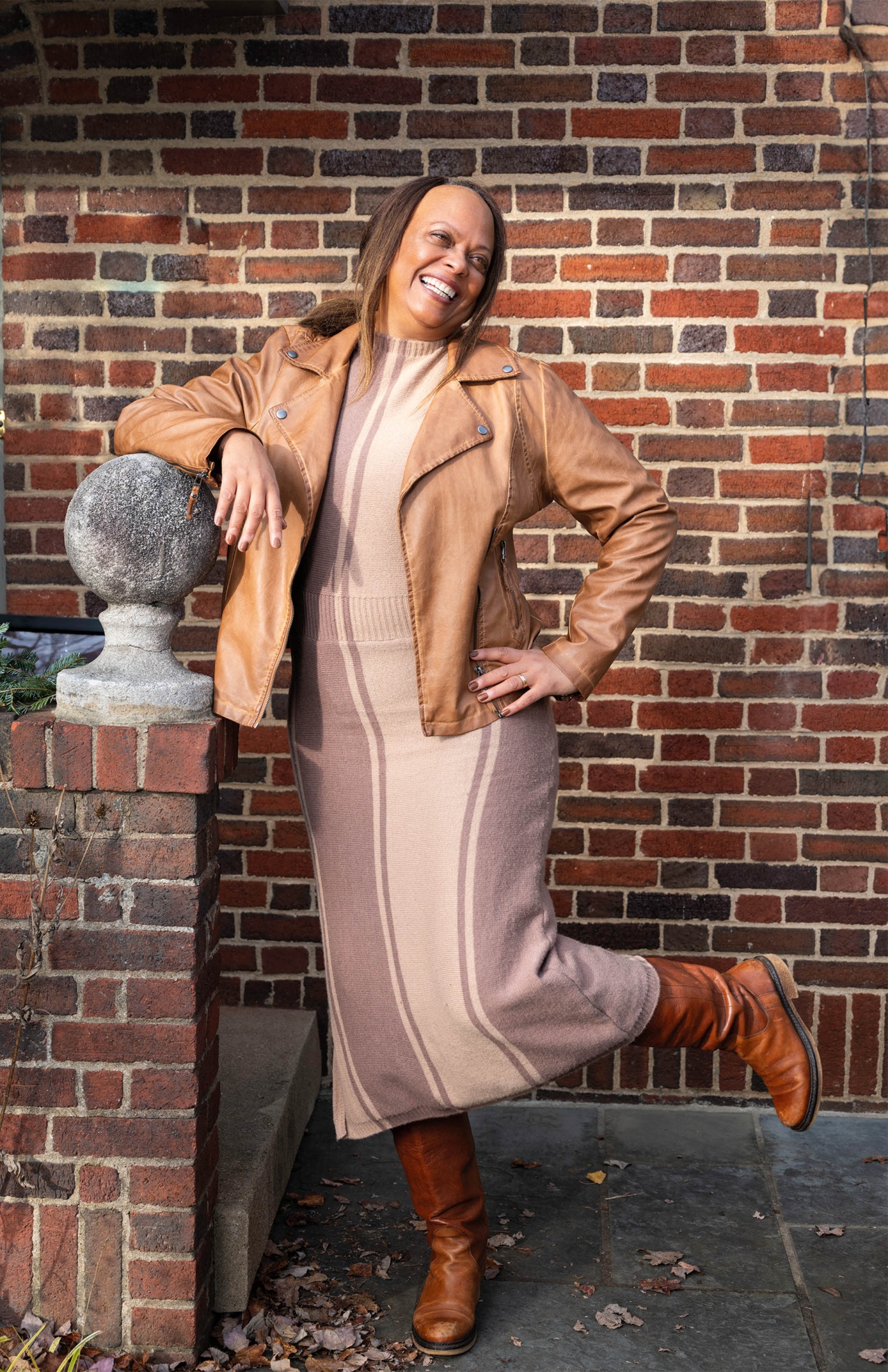 Image of Brenda Barbour smiling with her hand on her hip and a brick wall. 