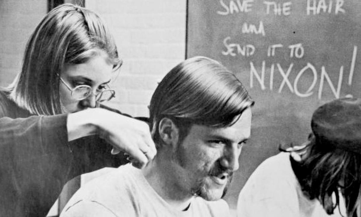 Archival image of a student cutting another student's hair in 1970.
