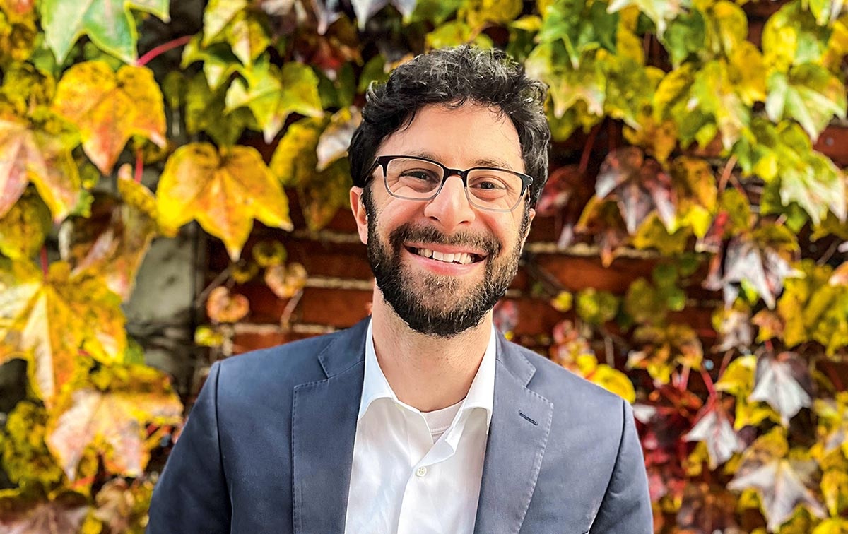 Image of Sidney Kushner in front of fall leaves on a brick wall