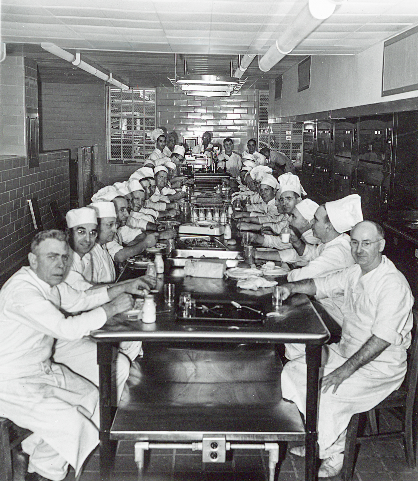 Ratty workers sit for dinner before service in the kitchen, 1050s