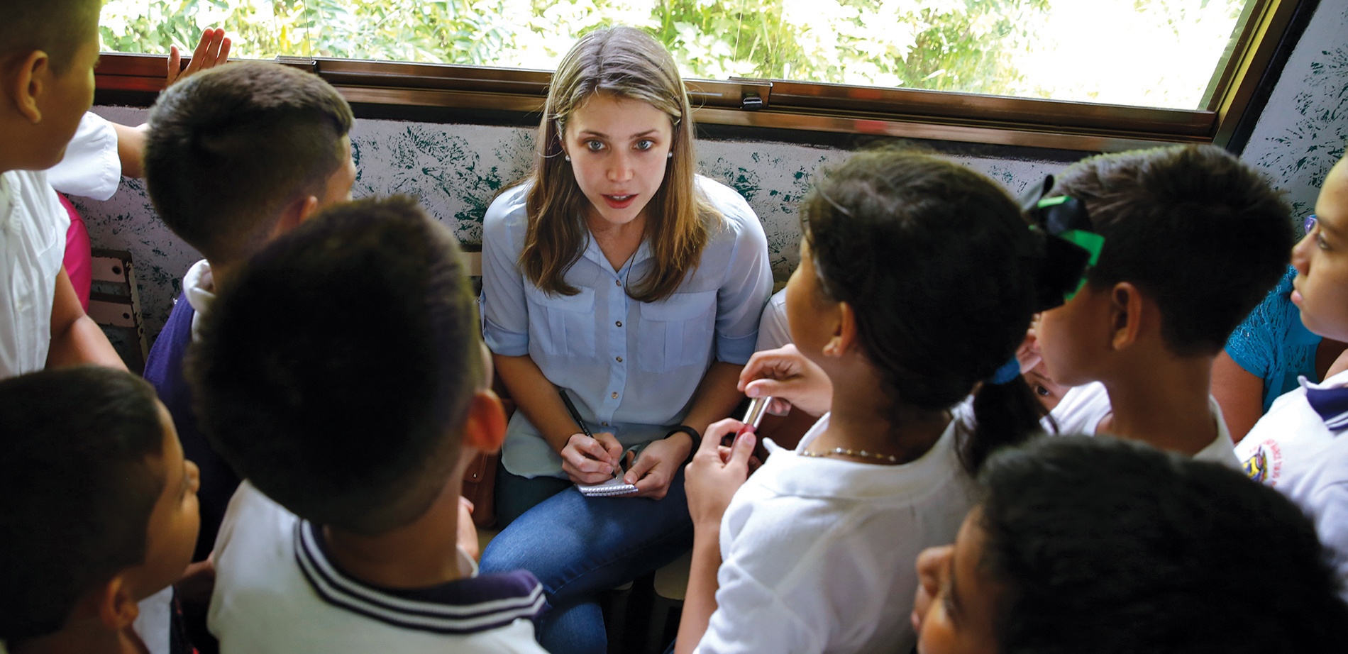 Image of Alexandra Ulmer taking notes, surrounded by Venezuelan children.