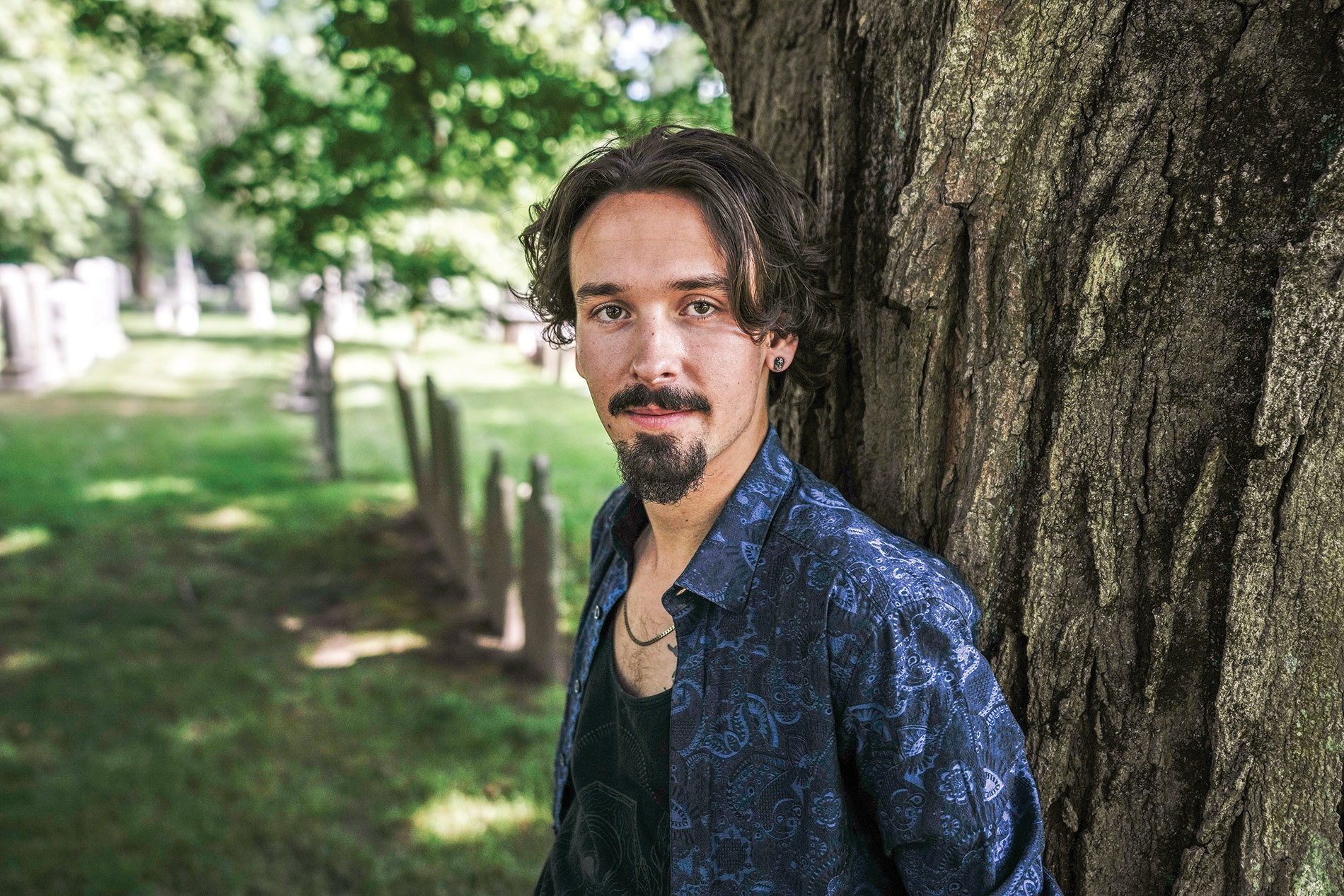 Image of Adrian Oteiza leaning against a tree in Swan Point Cemetery, Providence, Rhode Island