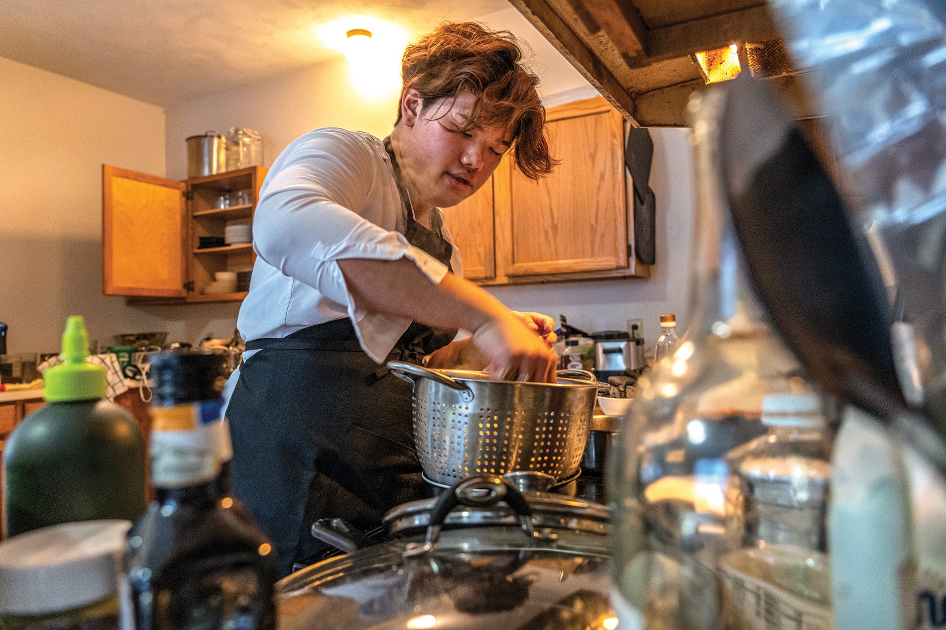 Image of Ryan Lum at the stove with pasta and a strainer