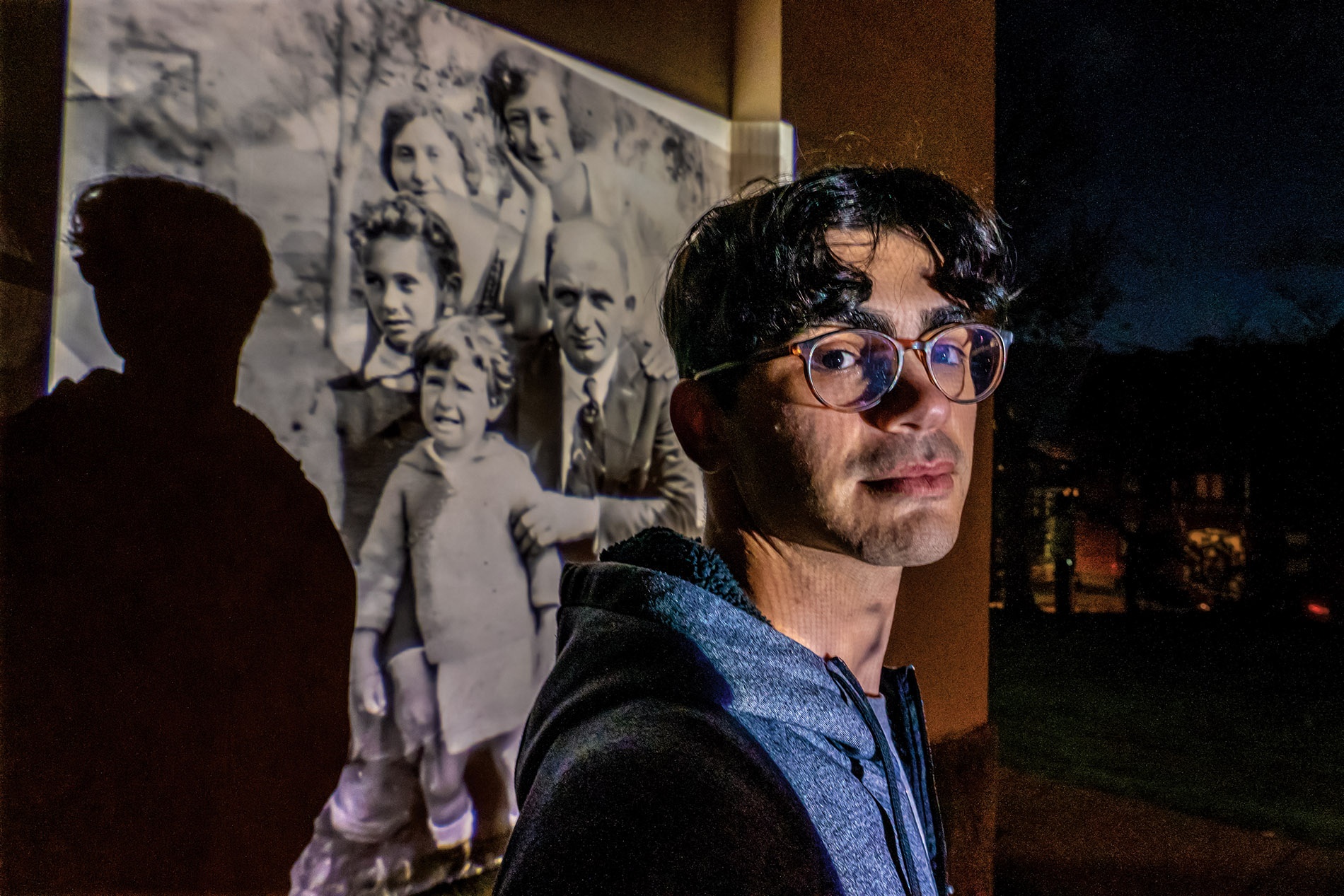 Image of Garfinkle with a photo projected behind him on a wall of his great-great-grandparents and their children, including his namesake, Jack. 