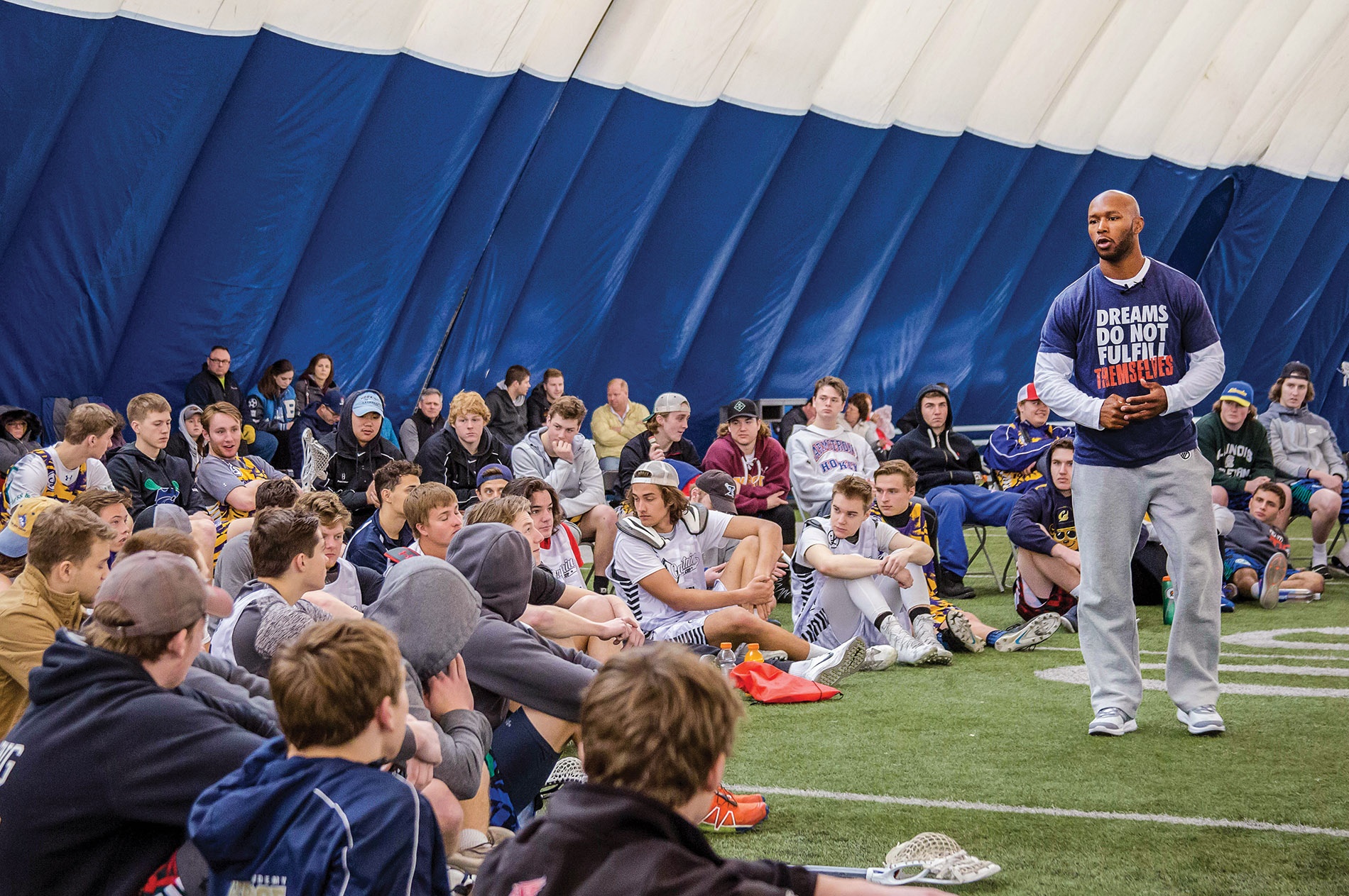 Image of Chazz Woodson speaking to players sitting on the ground