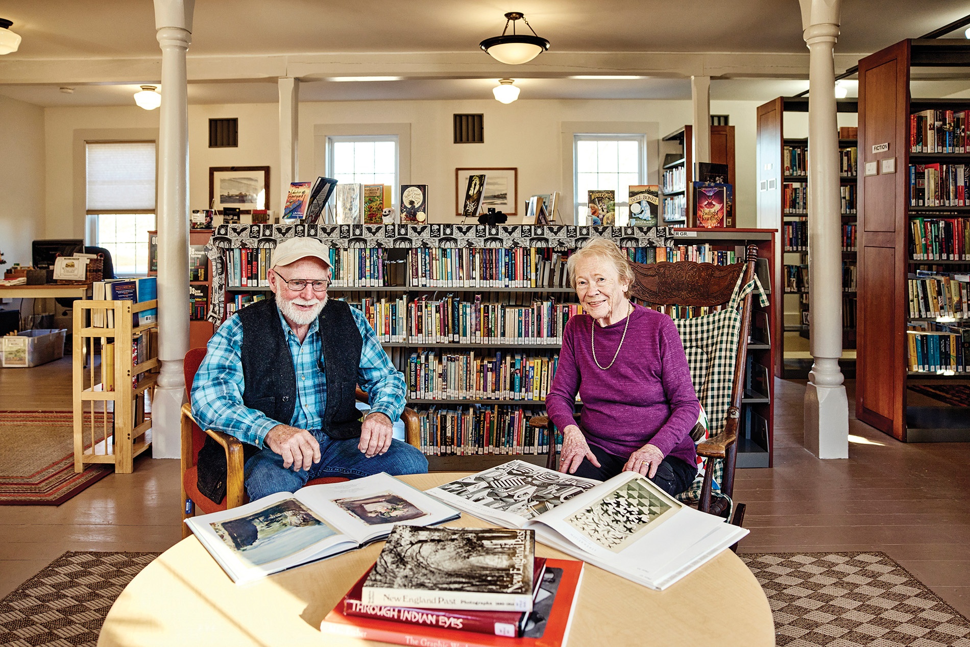 Image of Erik Ekholm and Ann Weiss sitting at a table surrounded by books in the Whitefield, Me.