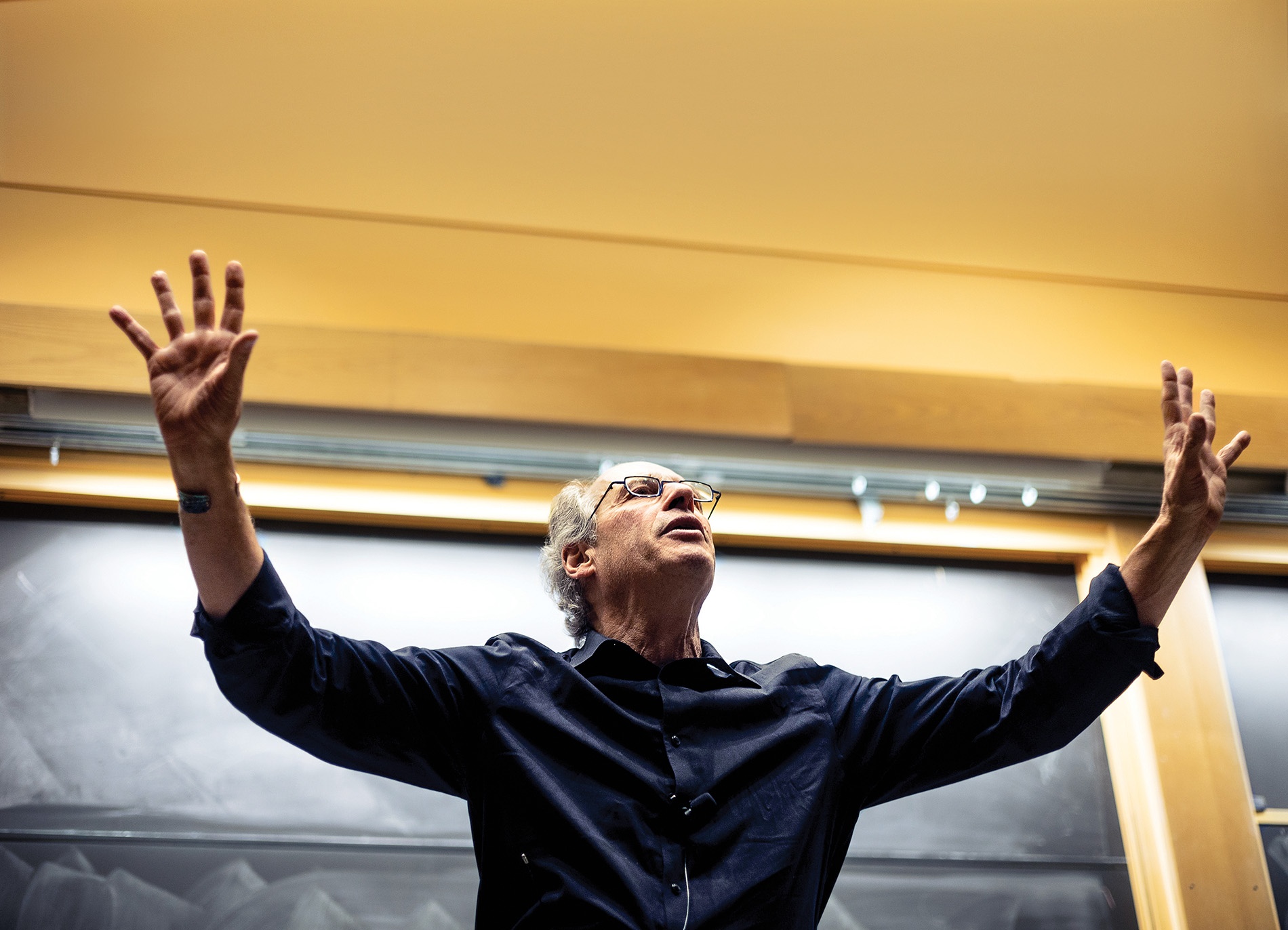 Image of Jim Marone teaching City Politics with his arms up and a chalkboard at his back in a classroom at Brown.