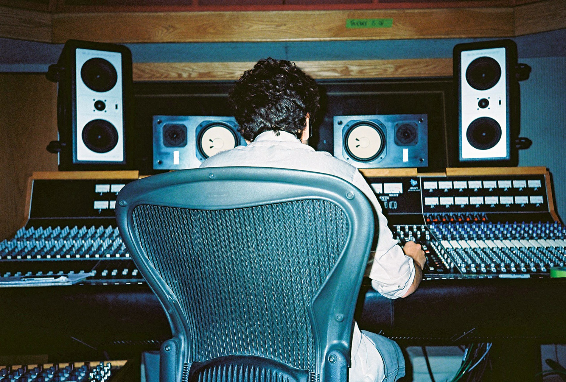 JJ Wiesler sitting back-to the camera at a soundboard.
