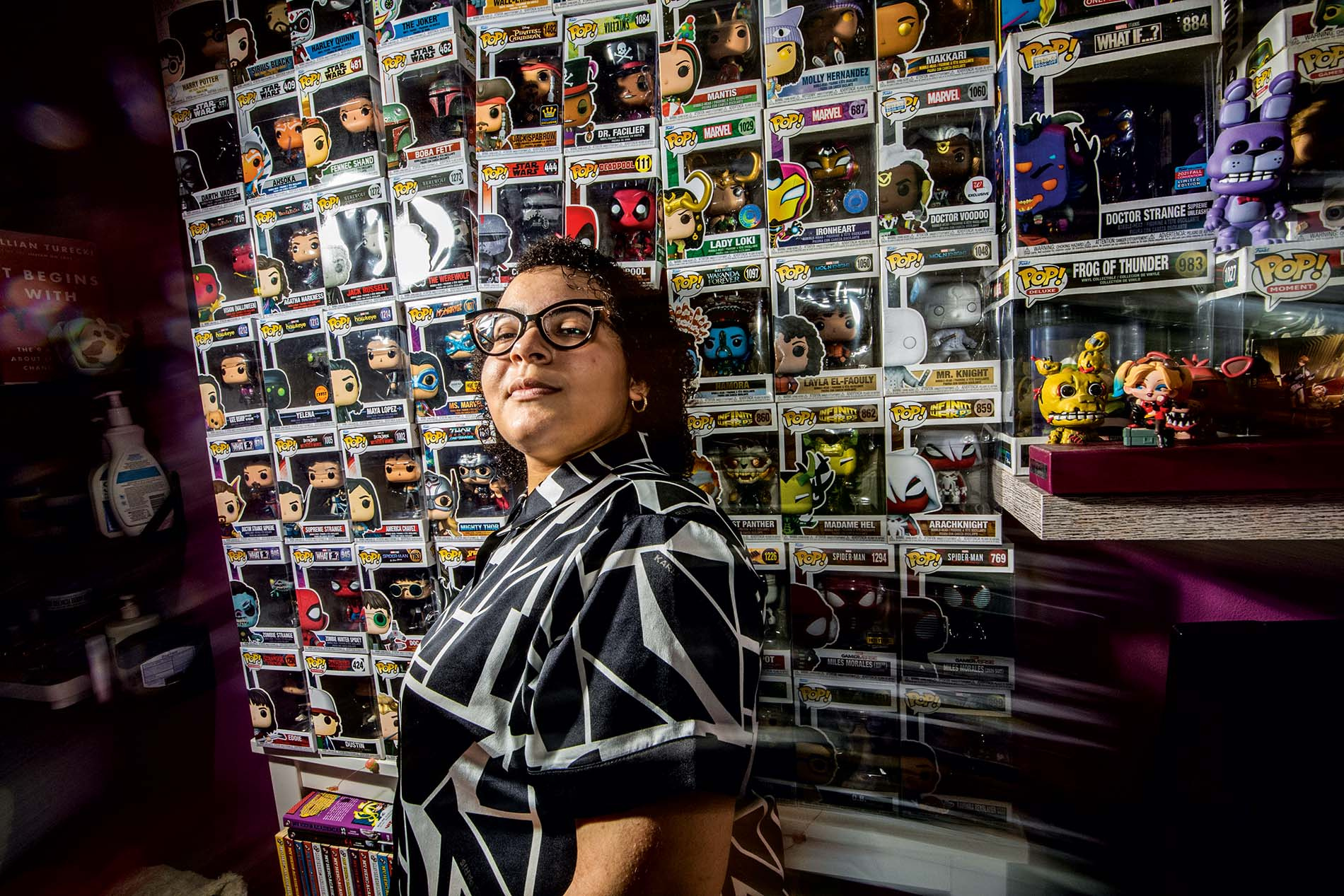 An image of Birana Bisono standing in front of a wall of Funko Pops