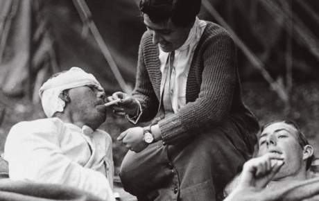 A WWI nurse lights the cigarette of a wounded soldier