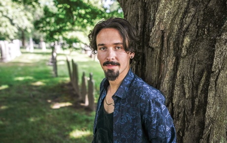 Image of Adrian Oteiza leaning against a tree in Swan Point Cemetery, Providence, Rhode Island