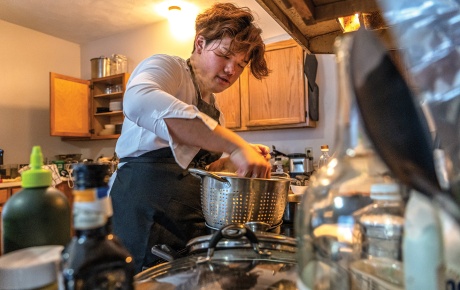 Image of Ryan Lum at the stove with pasta and a strainer