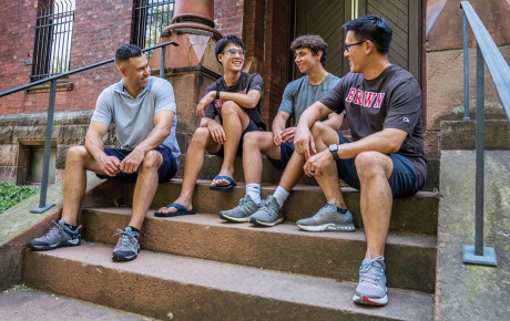 Image of two Brown alumni sitting on the steps on Brown campus with their two sons