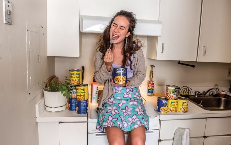 Image of Marielle Buxbaum sitting on the counter in her kitchen with cans of garbanzo beans.