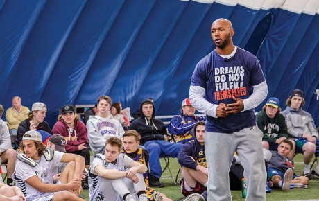 Image of Chazz Woodson speaking to players sitting on the ground