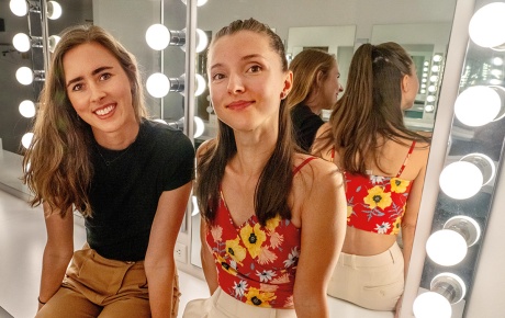 Image of Kayleigh Donowski and Eugenia Zinovieva sitting in front of a lighted mirror