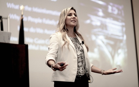 Imge of Lena Sisco speaking on stage with a screen behind her