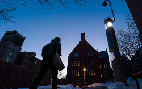 a student walks through campus lit by a security kiosk
