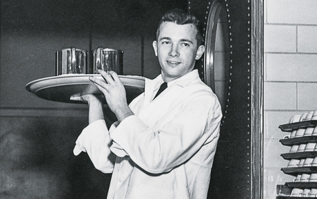 a waiter comes through a doorway with a tray on his shoulder at the Ratty 